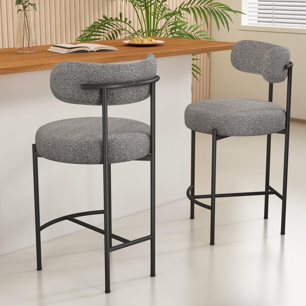 Two gray bar stools with black metal frames in a room with a wooden table and plants.