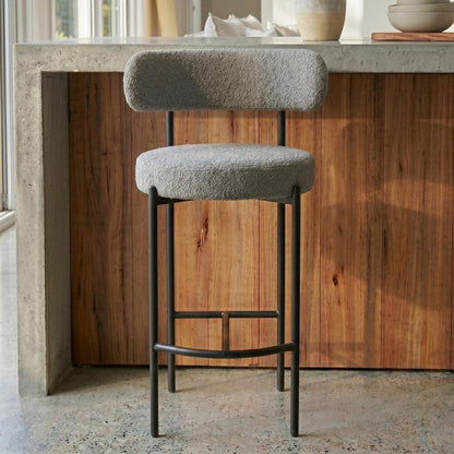 Bar stool with a textured cushioned seat and backrest in a kitchen setting.