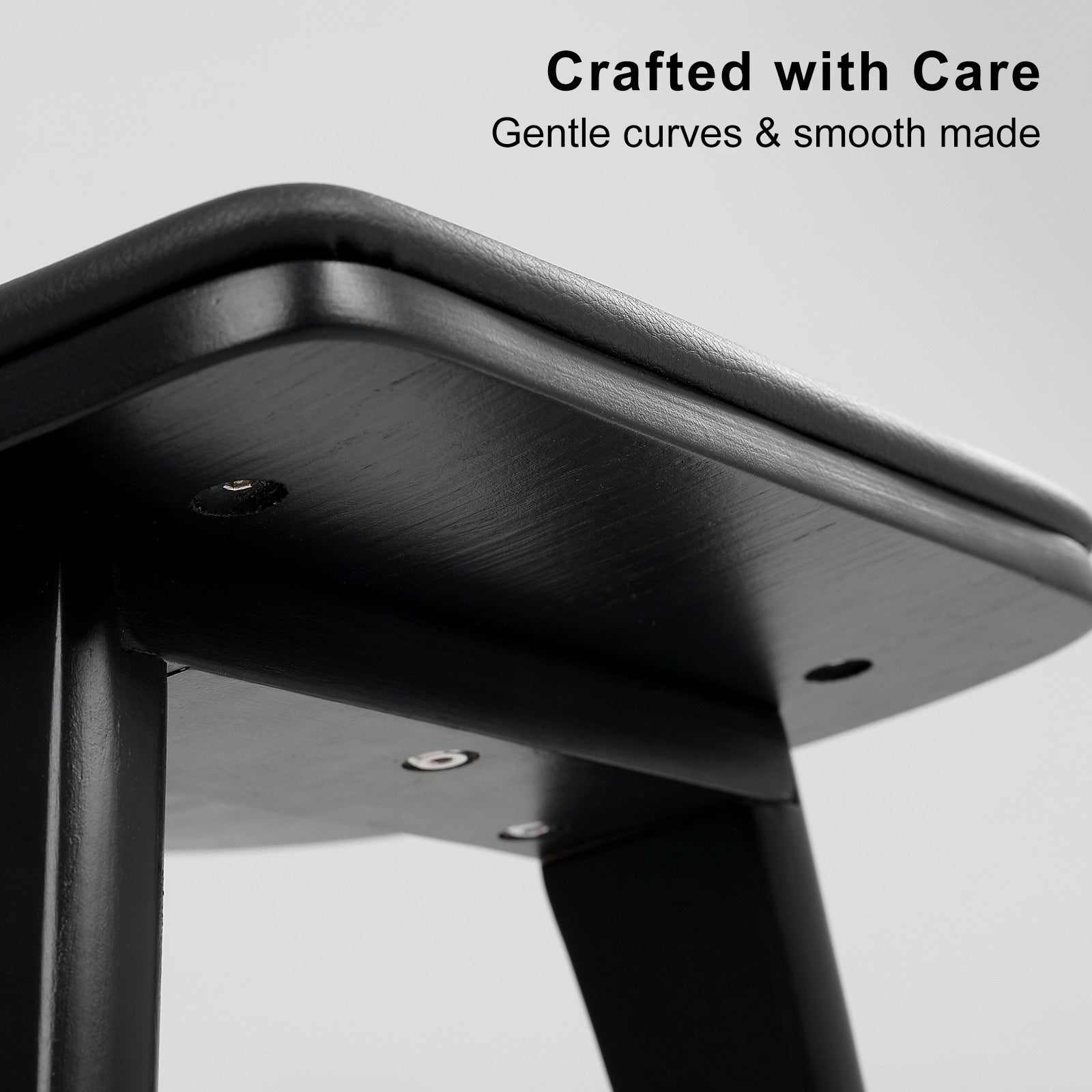 Close-up of a black metal stool with 'Crafted with Care' text on a gray background