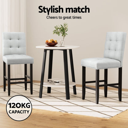 Dining set with two grey fabric bar stools and a small round table on a wooden floor.
