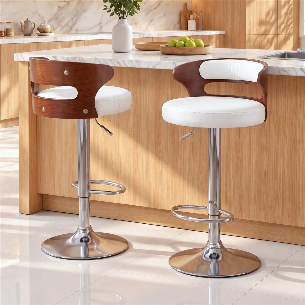 Two Juna white pu leather swivel bar stools with walnut-look backrests positioned beside a white marble kitchen island.