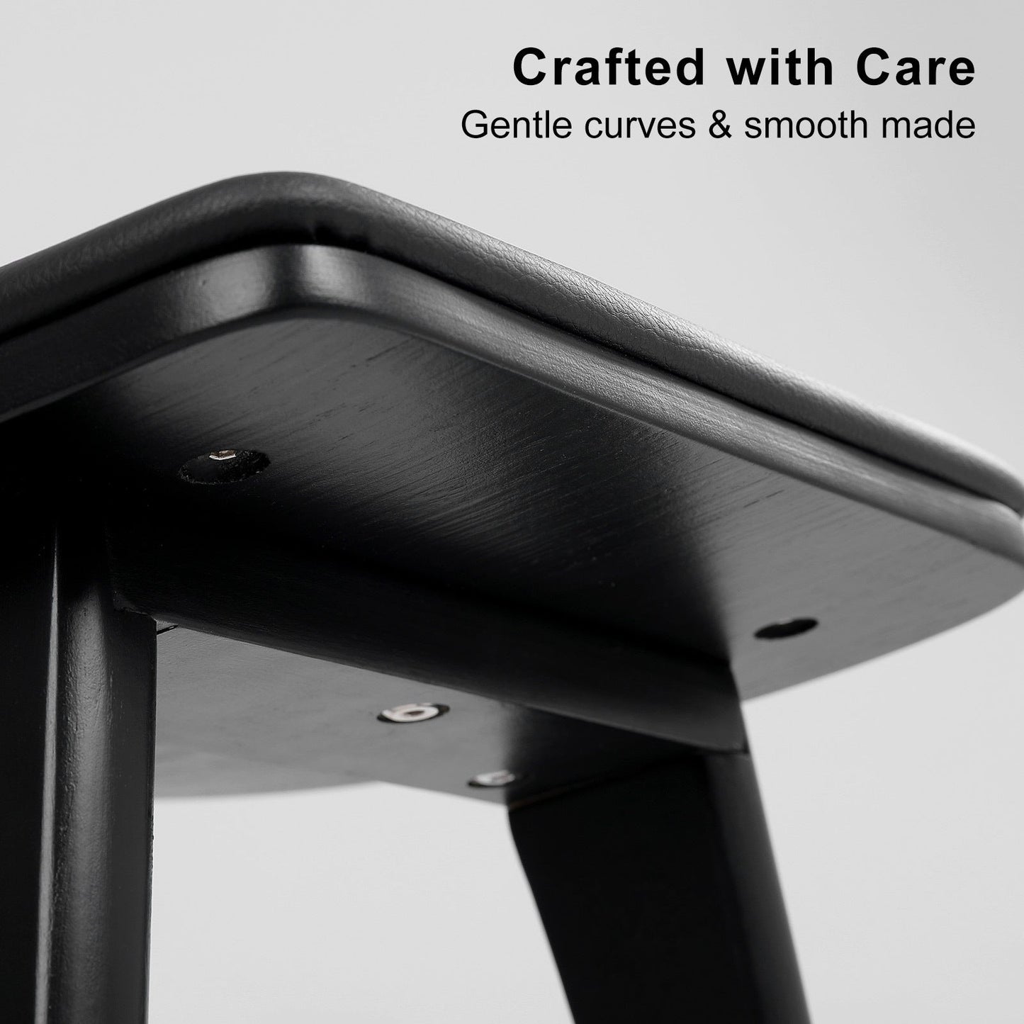 Close-up of a black metal stool with 'Crafted with Care' text on a gray background