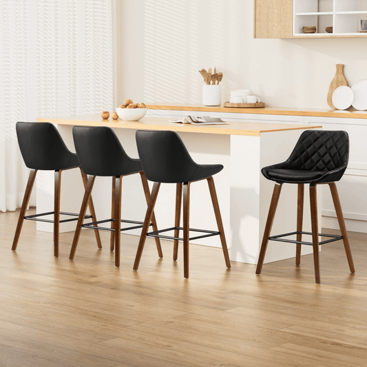 Black bar stools with wooden legs around a kitchen island.
