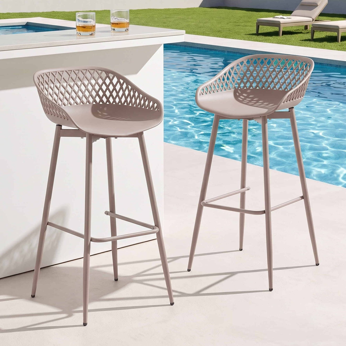 Two beige Kian outdoor bar stools beside a pool and white outdoor bar.
