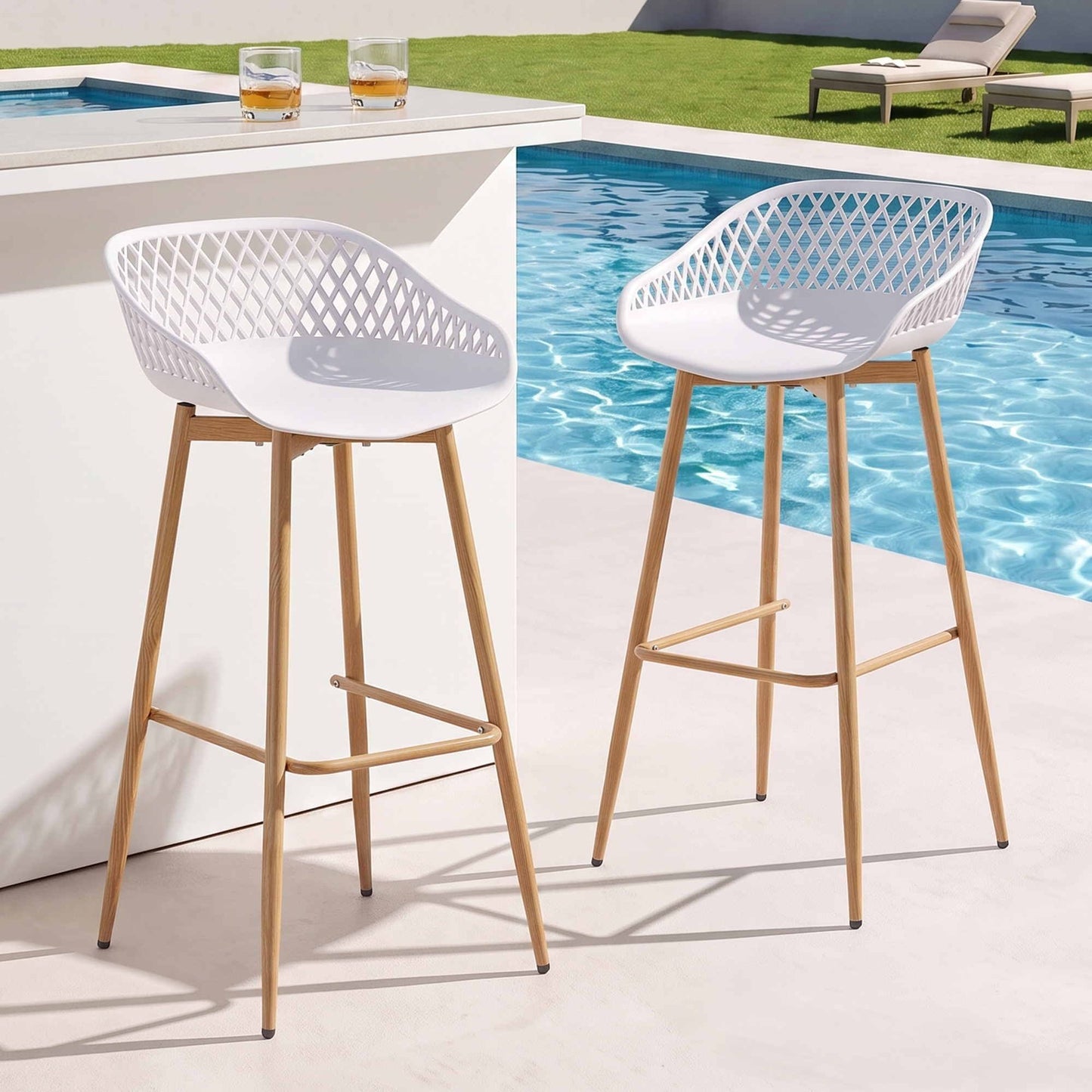 Two white Kian outdoor bar stools beside a pool and white outdoor bar.