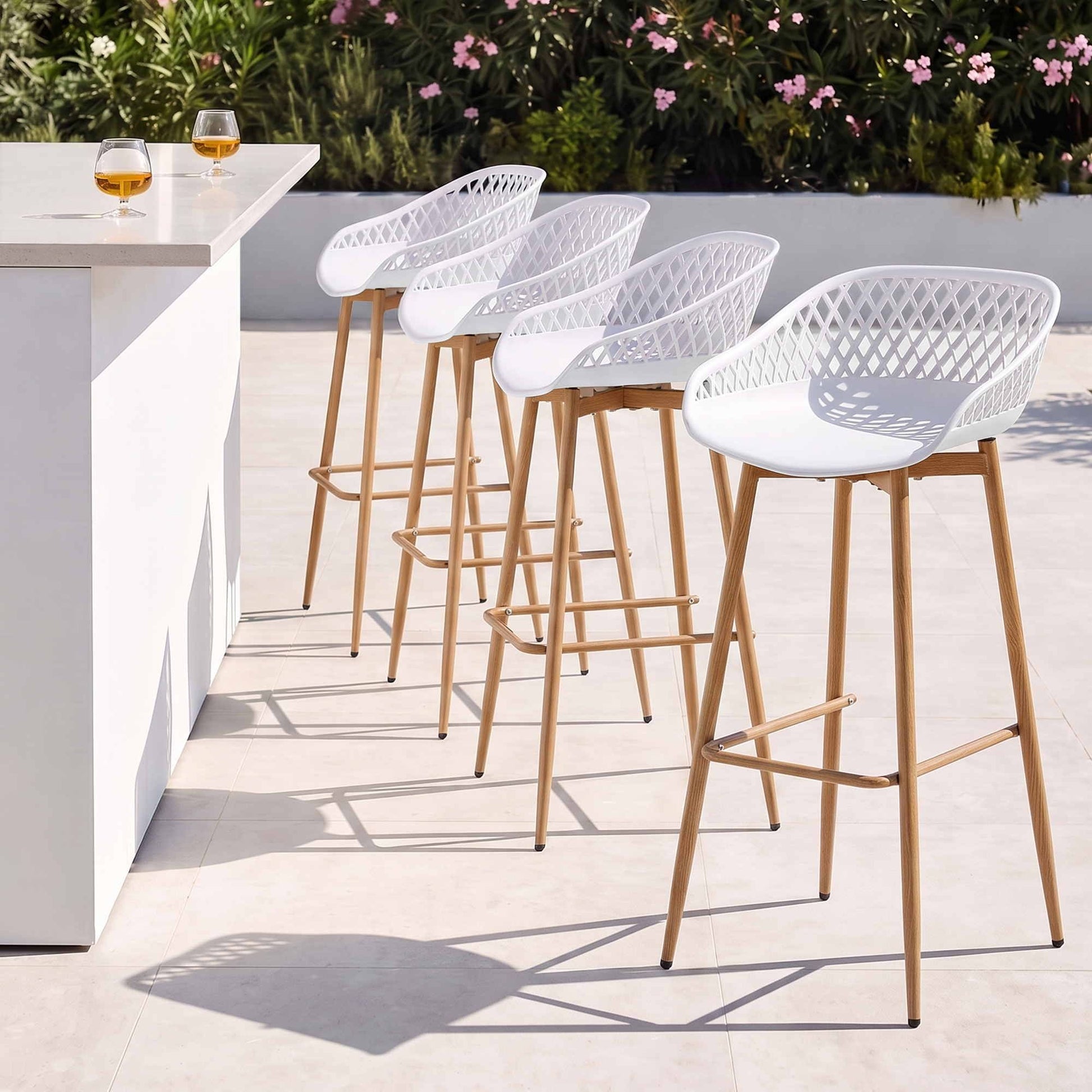 Four white Kian outdoor bar stools beside a white outdoor bar counter.