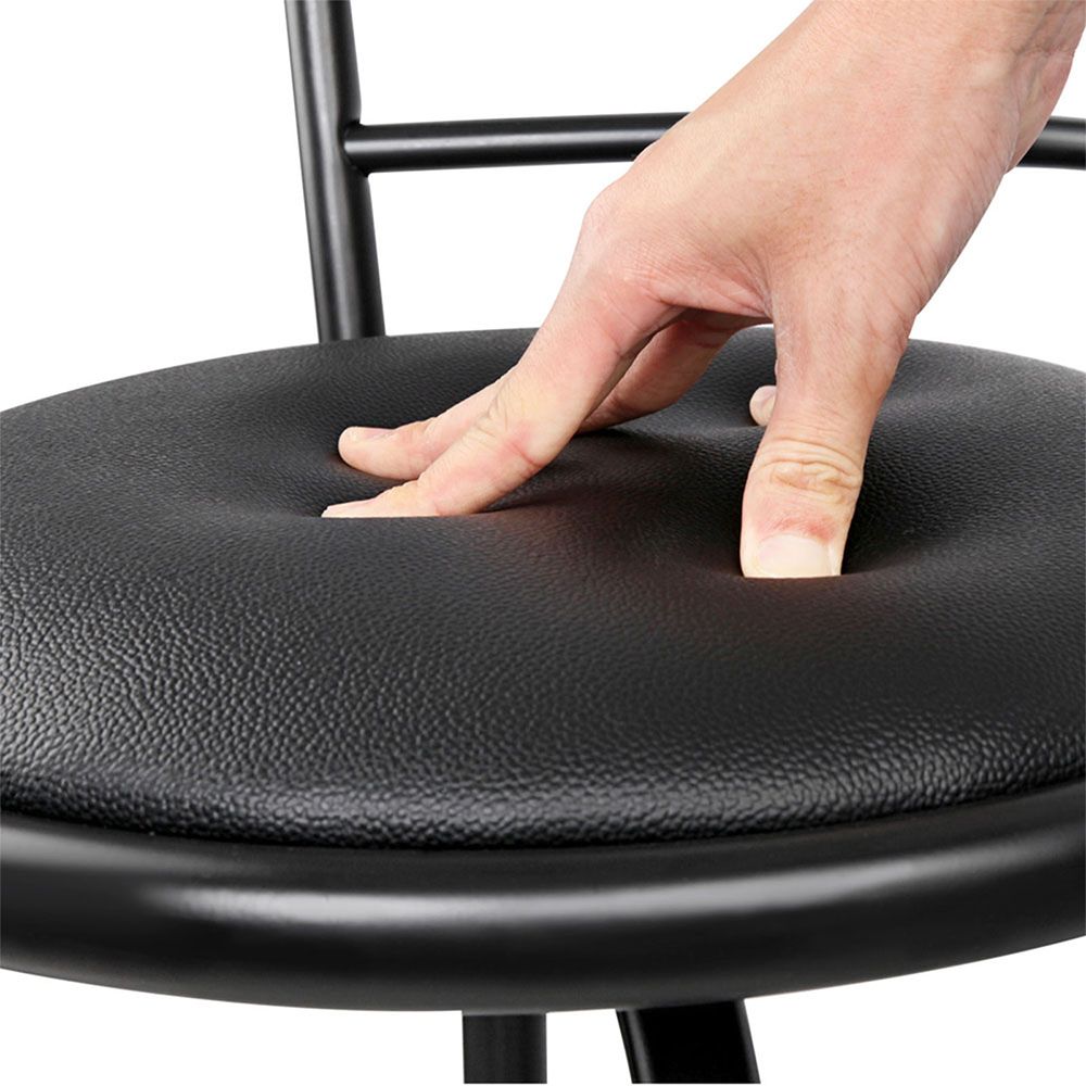 Hand pressing down on a black chair seat cushion to demonstrate its softness.