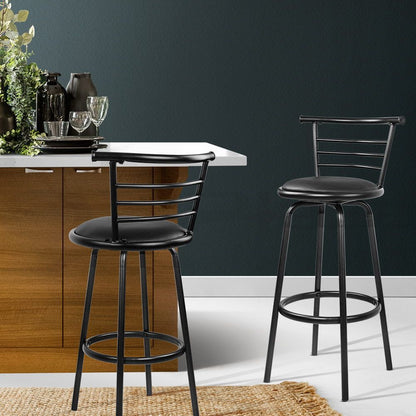 Two black bar stools in a kitchen setting with a dark wall and wooden cabinets.