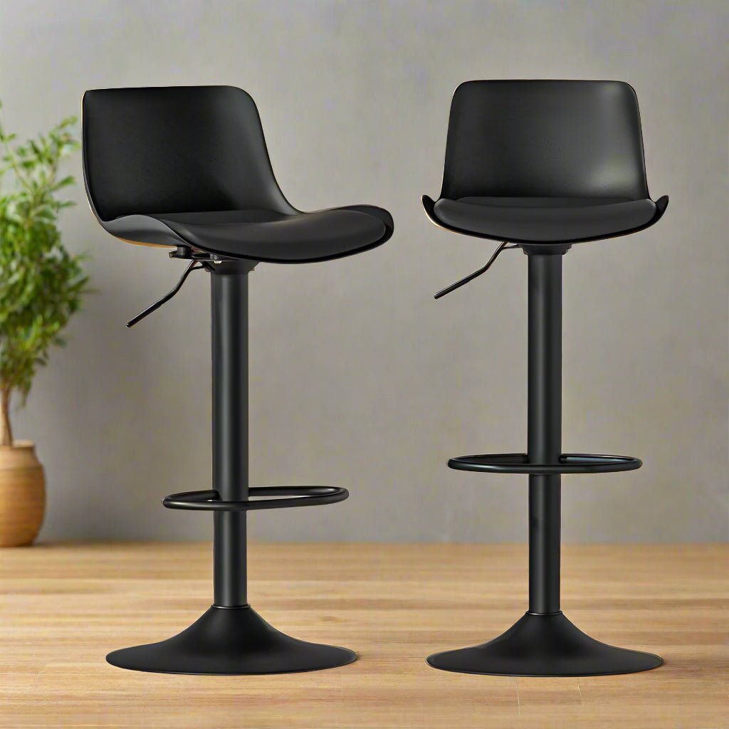Two black swivel bar stools on a wooden surface with a neutral background