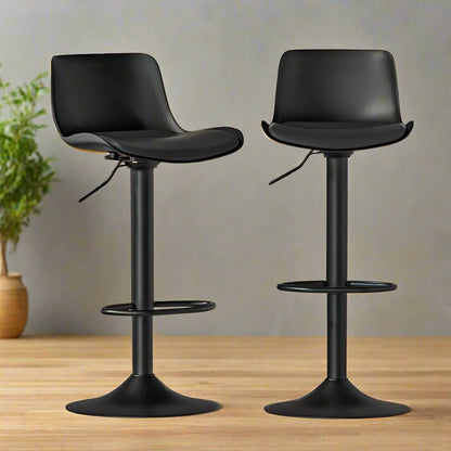 Two black swivel bar stools on a wooden surface with a neutral background