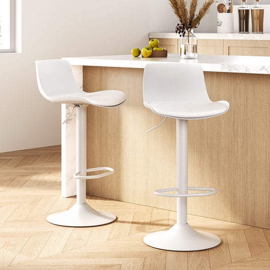 Two white swivel bar stools in front of a kitchen counter with a light wood floor.