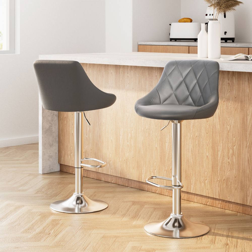 Two grey bar stools with metallic bases in a kitchen setting.
